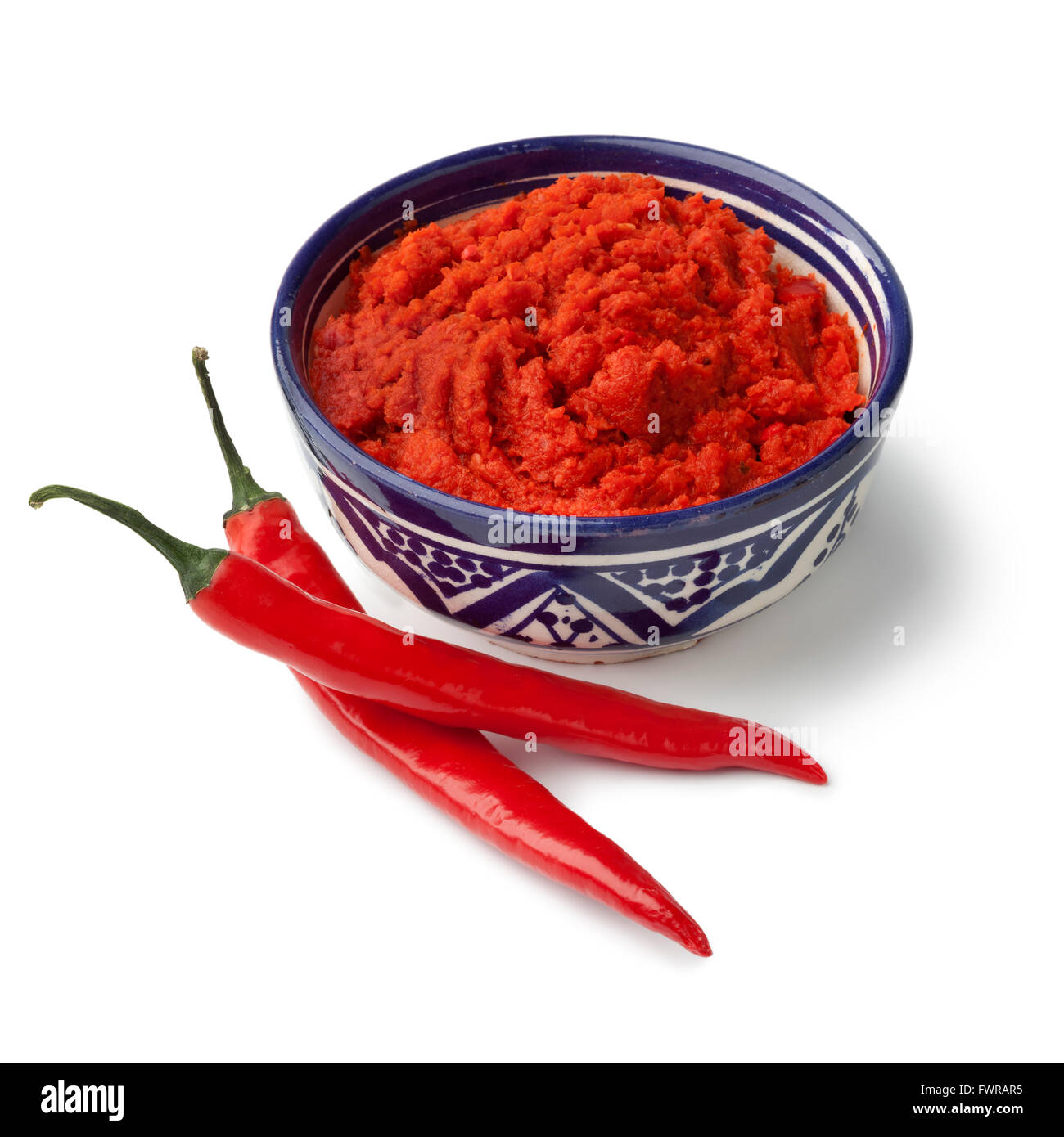 Ciotola con rosso di harissa marocchina e fresco peperoncino rosso su sfondo bianco Foto Stock