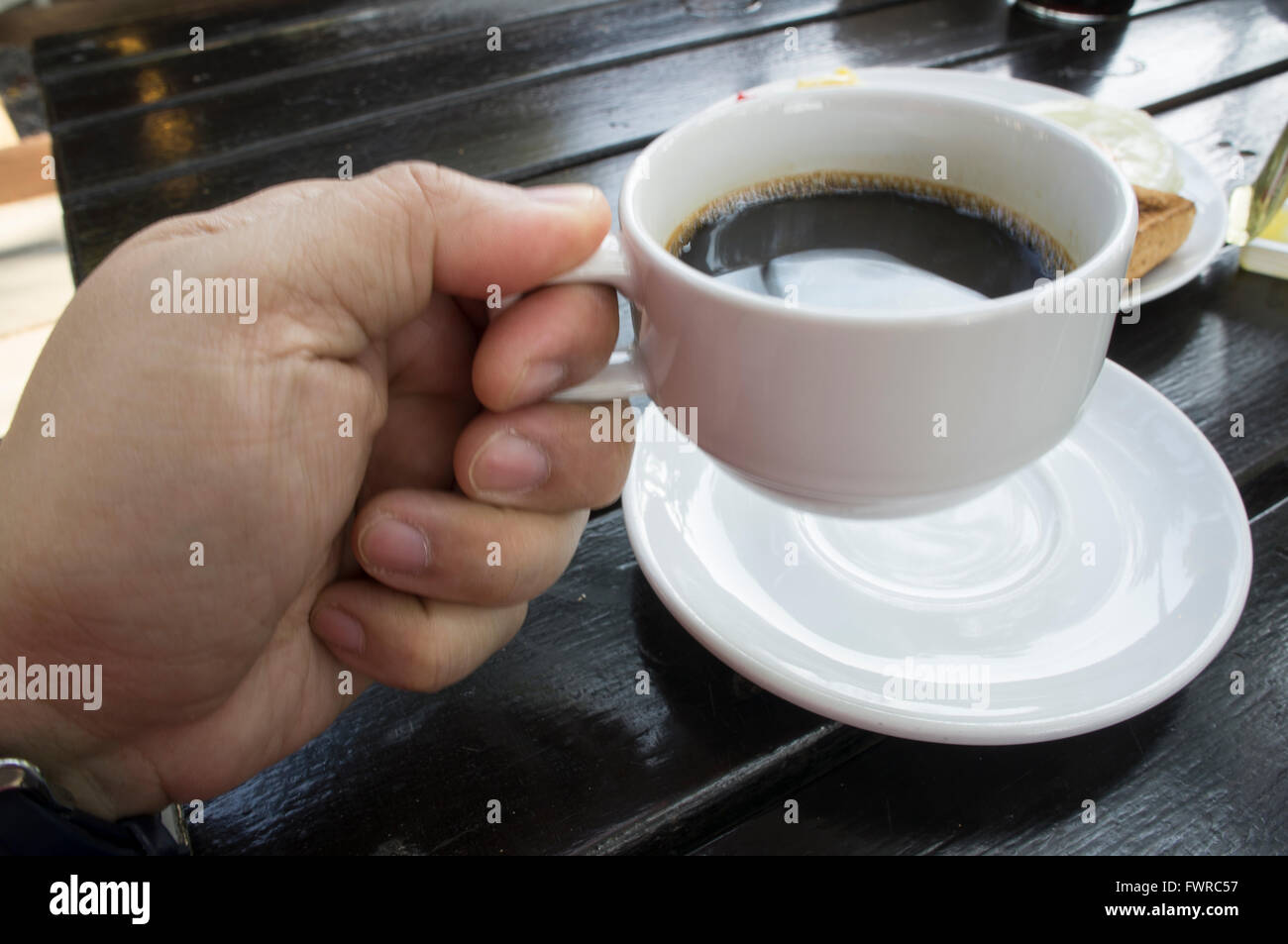 Man mano sollevare tazza di caffè la mattina Foto Stock