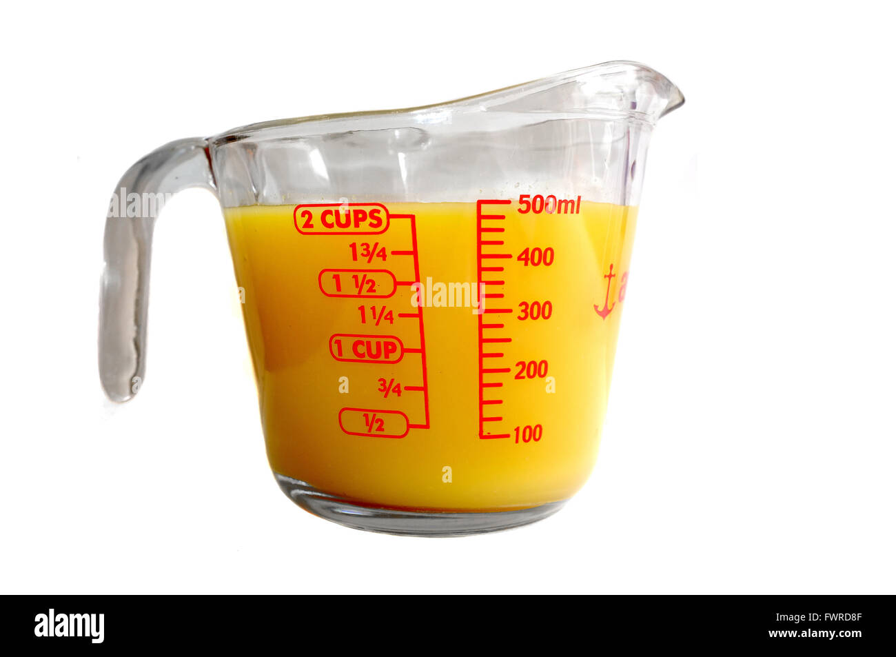 Una misura di Pyrex brocca piena di orange liquido colorato fotografati contro uno sfondo bianco. Foto Stock