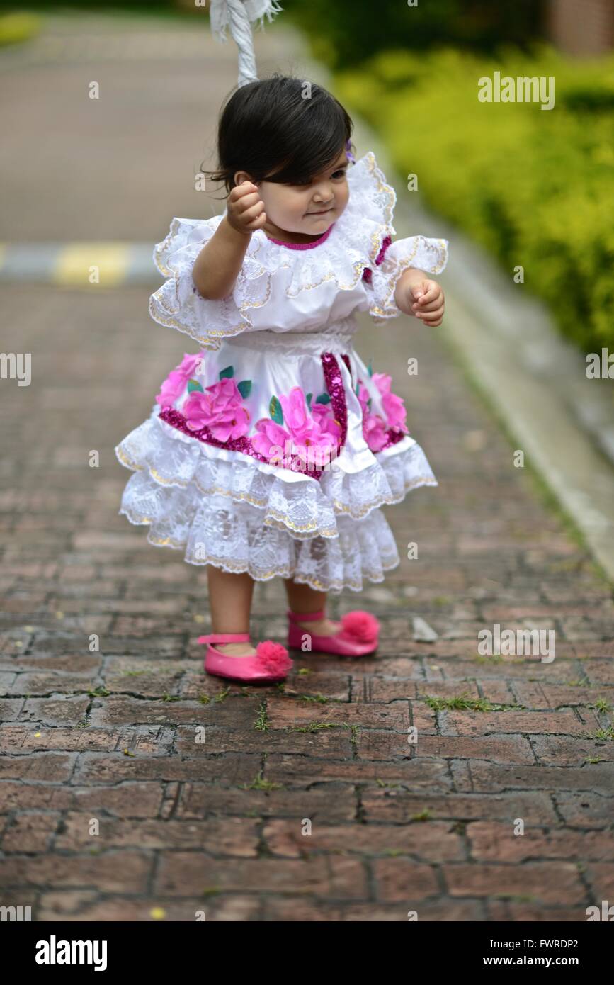 Ragazza ad imparare a camminare. Un anno di età ragazza vestita con il tradizionale abito colombiano dalla regione di Huila. Foto Stock