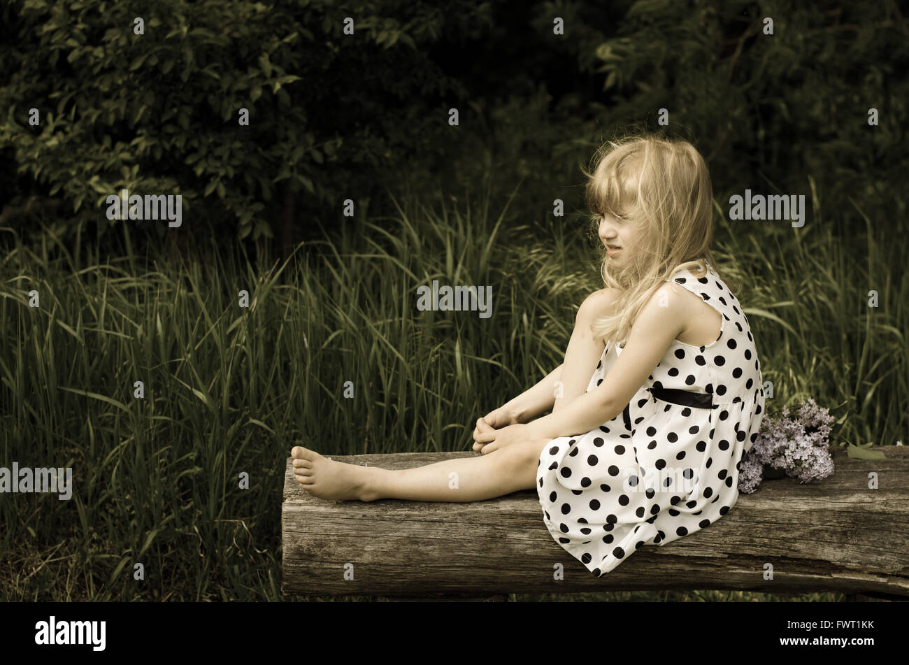 Bella ragazza bionda seduta sul banco di legno Foto Stock