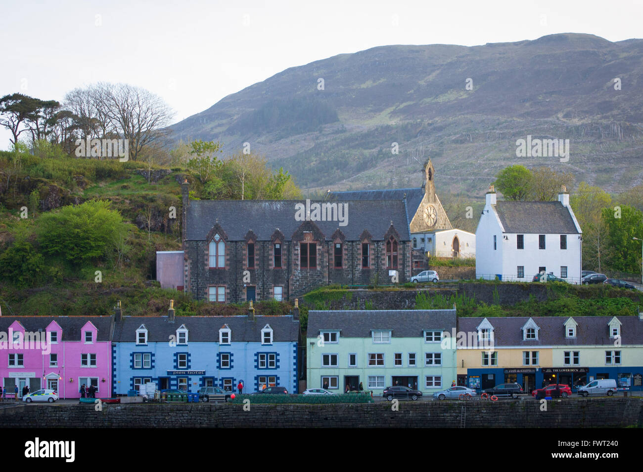 Una vista di colorati negozi e la chiesa di Porto Portree sull'Isola di Skye in Scozia. Foto Stock