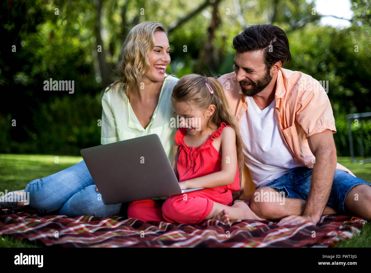I genitori con la figlia utilizzando il portatile in cantiere Foto Stock