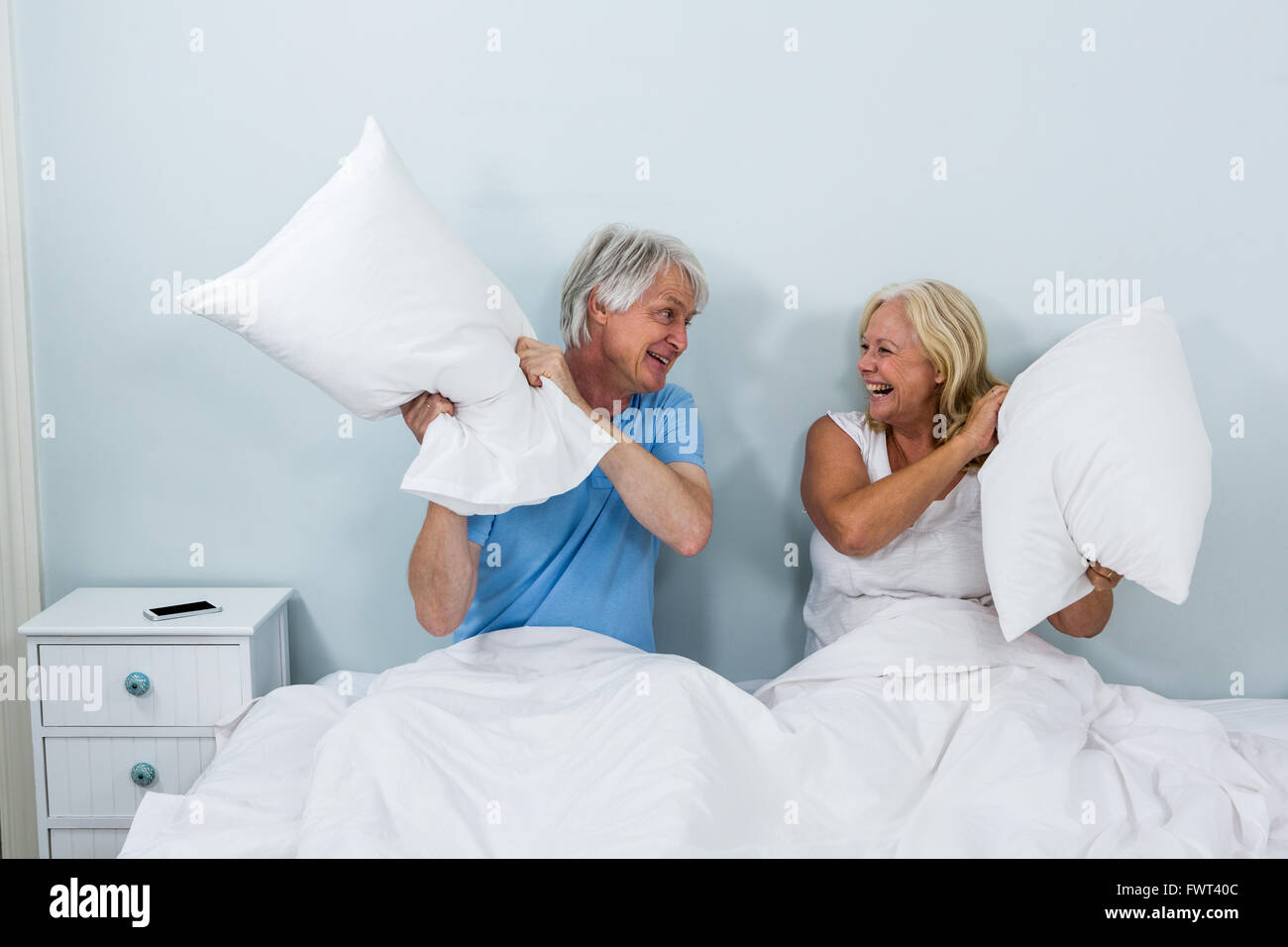 Felice coppia senior giocando con cuscini in camera da letto Foto Stock