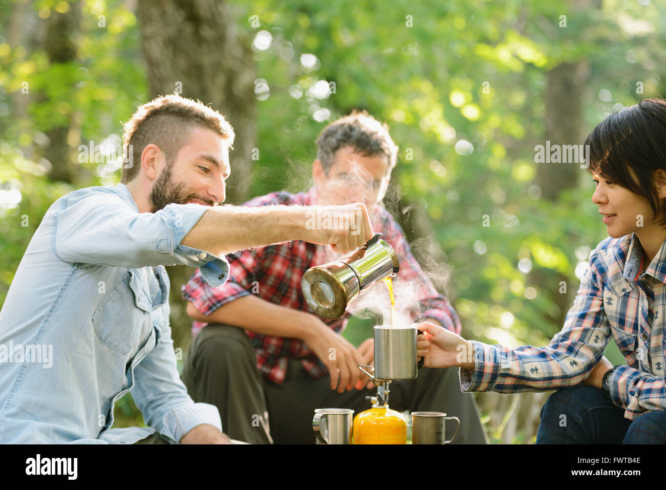 Multi-etnico gruppo di amici avente un caffè a un campeggio Foto Stock