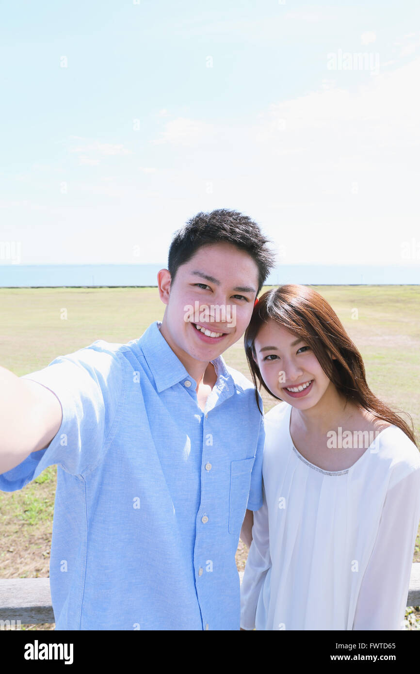 Un giovane giapponese giovane tenendo selfie dal mare Foto Stock