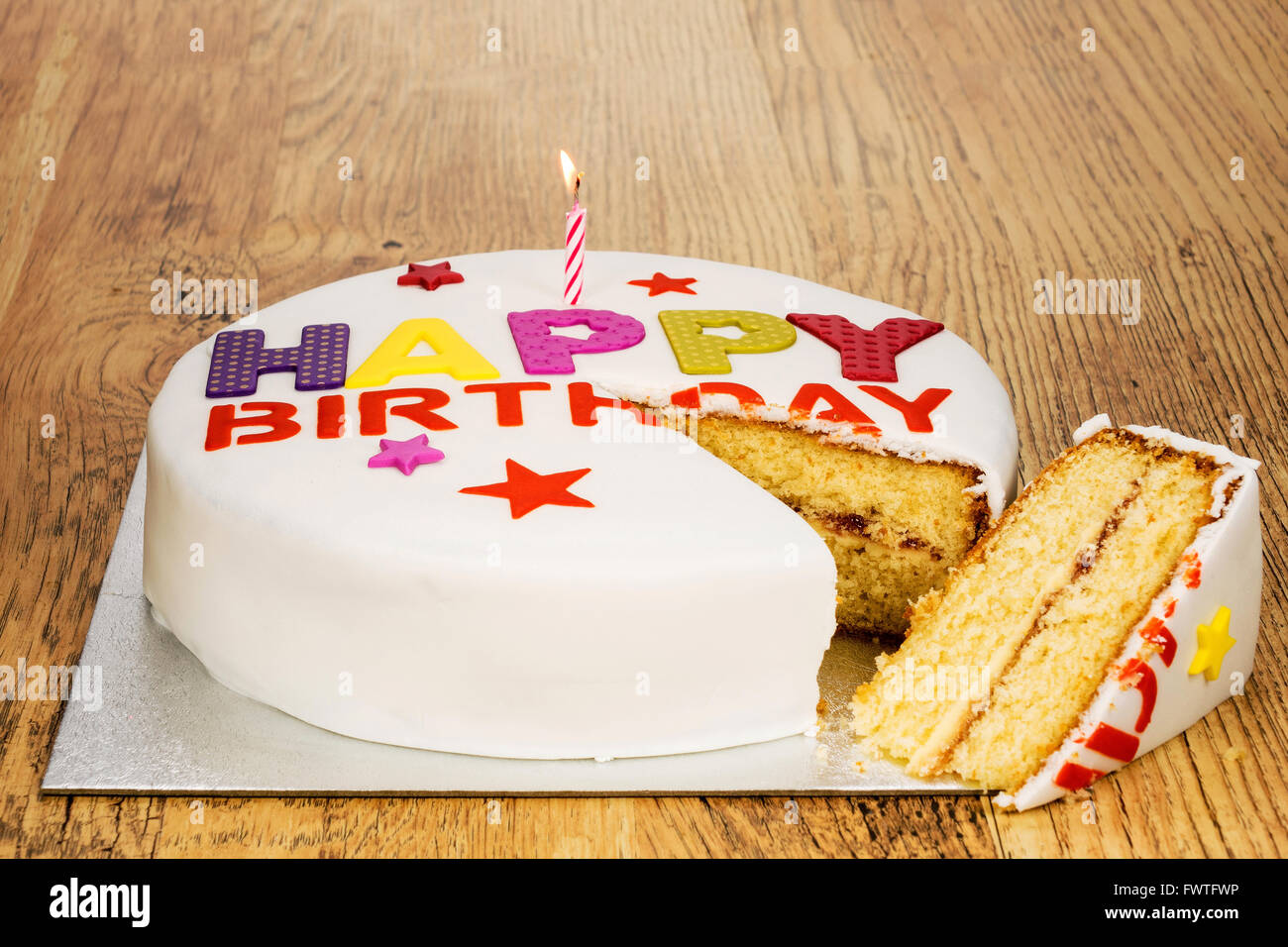 Una torta di compleanno con una candela e una fetta tagliata fuori di esso. Foto Stock