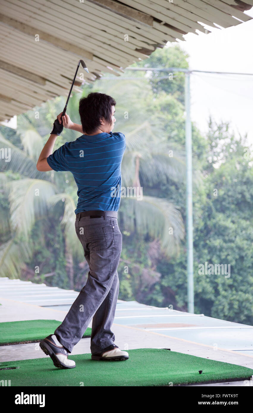 Giovane maschio golfista praticando il suo drive Foto Stock