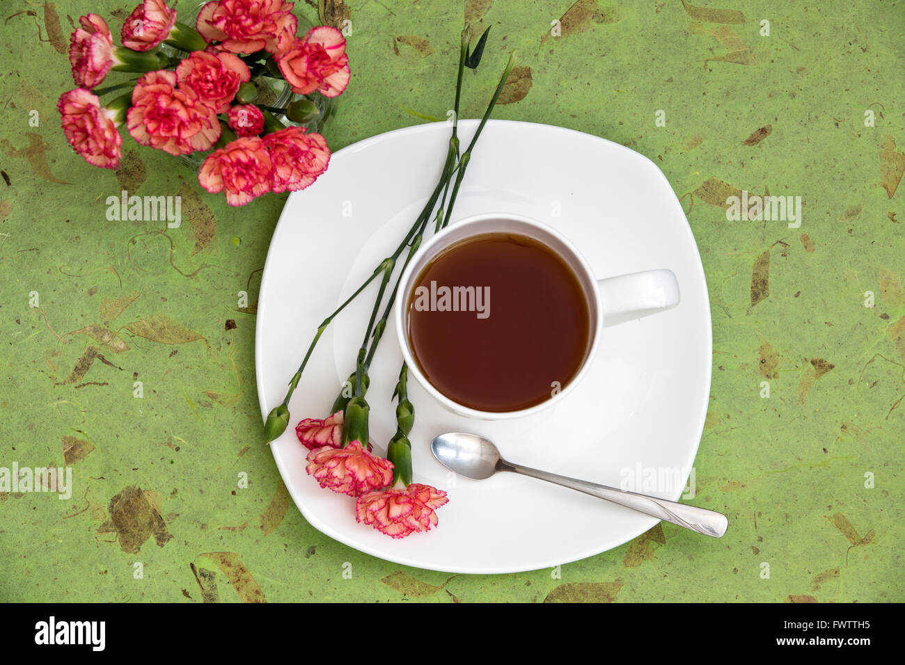 Piccolo bouquet di garofani impostato da una tazza di tè Foto Stock