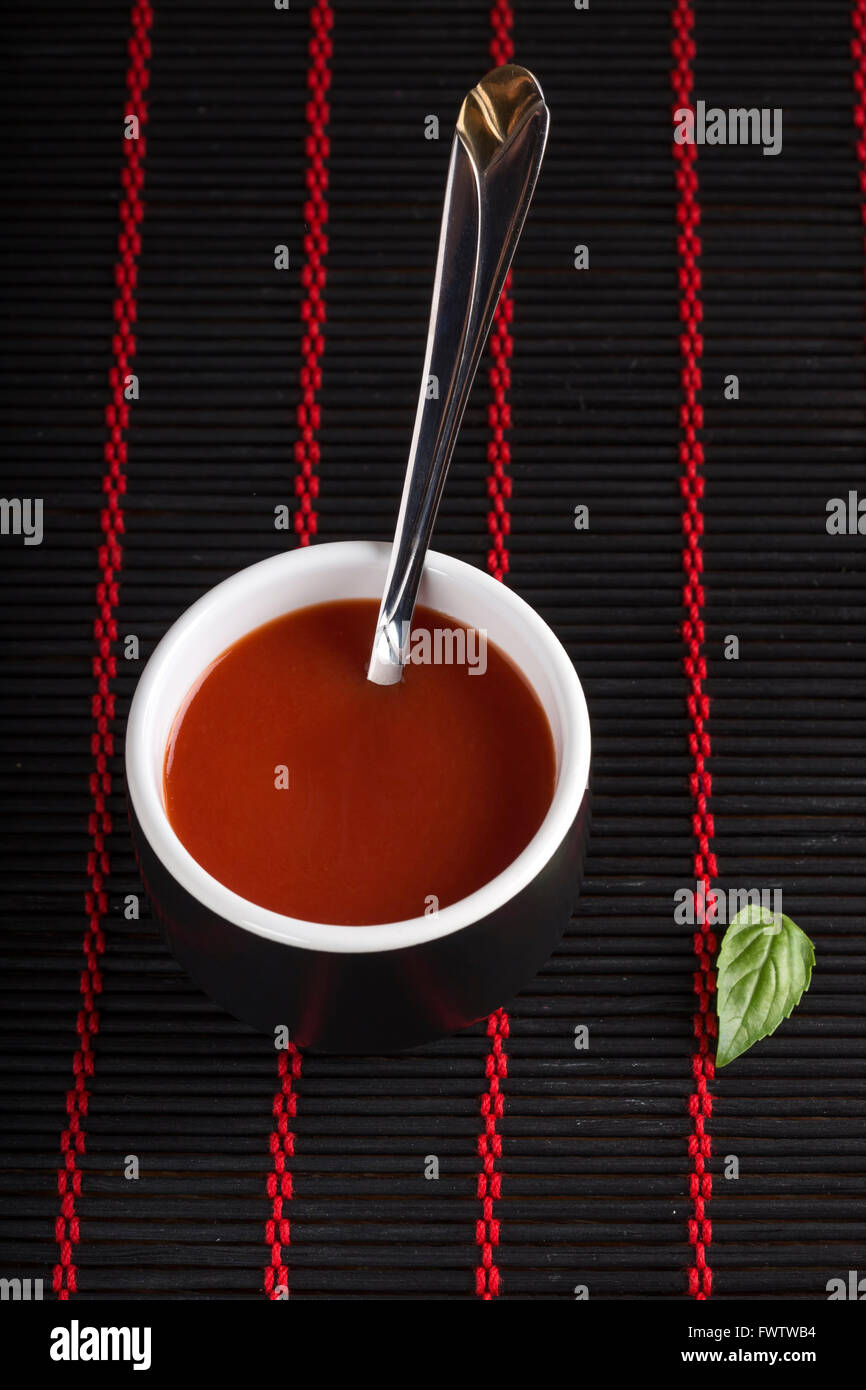 In casa, la salsa di pomodoro fresco in vaso nero con cucchiaino Foto Stock