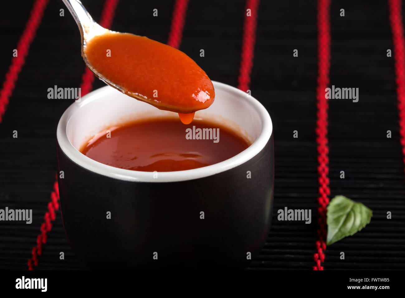In casa, la salsa di pomodoro fresco in vaso nero con cucchiaino Foto Stock