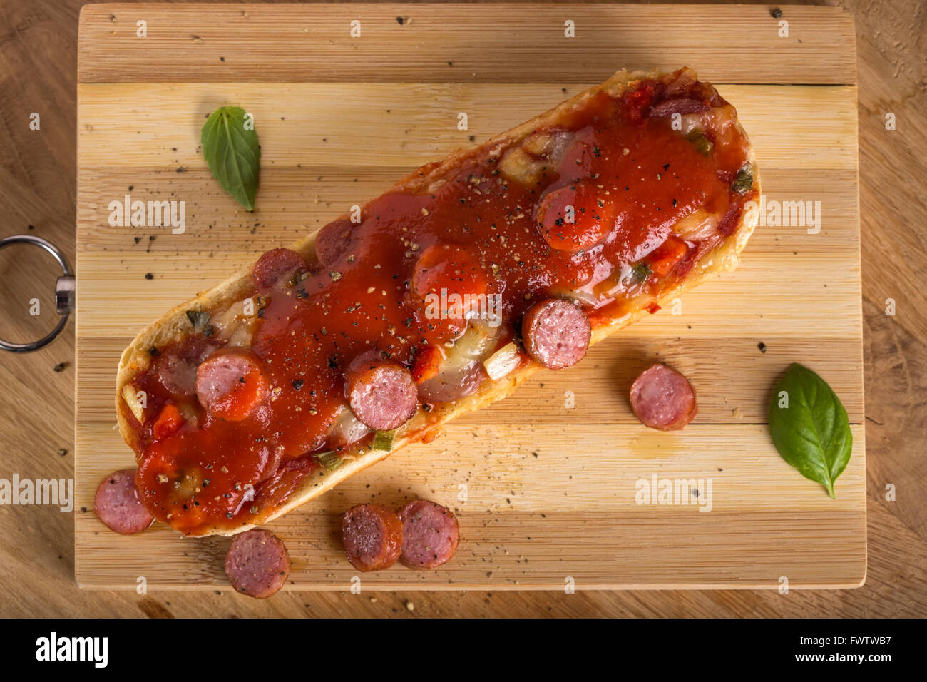 Pizza baguette con salsa di pomodoro sul tagliere di legno Foto Stock