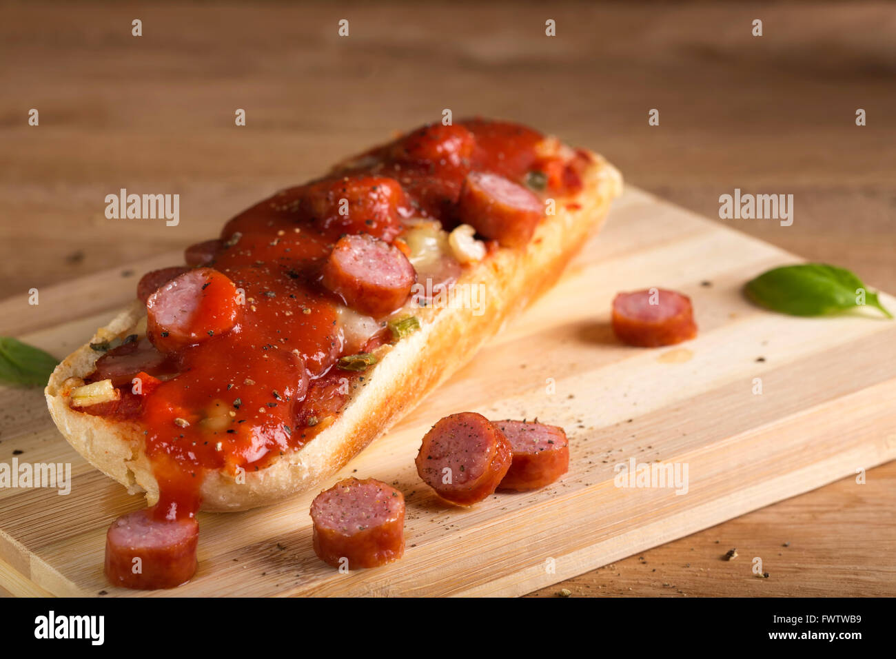 Pizza baguette con salsa di pomodoro sul tagliere di legno Foto Stock