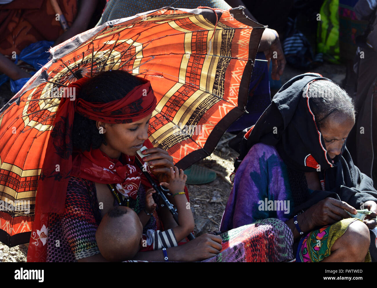 Donne Oromo sotto l'ombrello coloratissimo mercato settimanale bati, Etiopia. Foto Stock