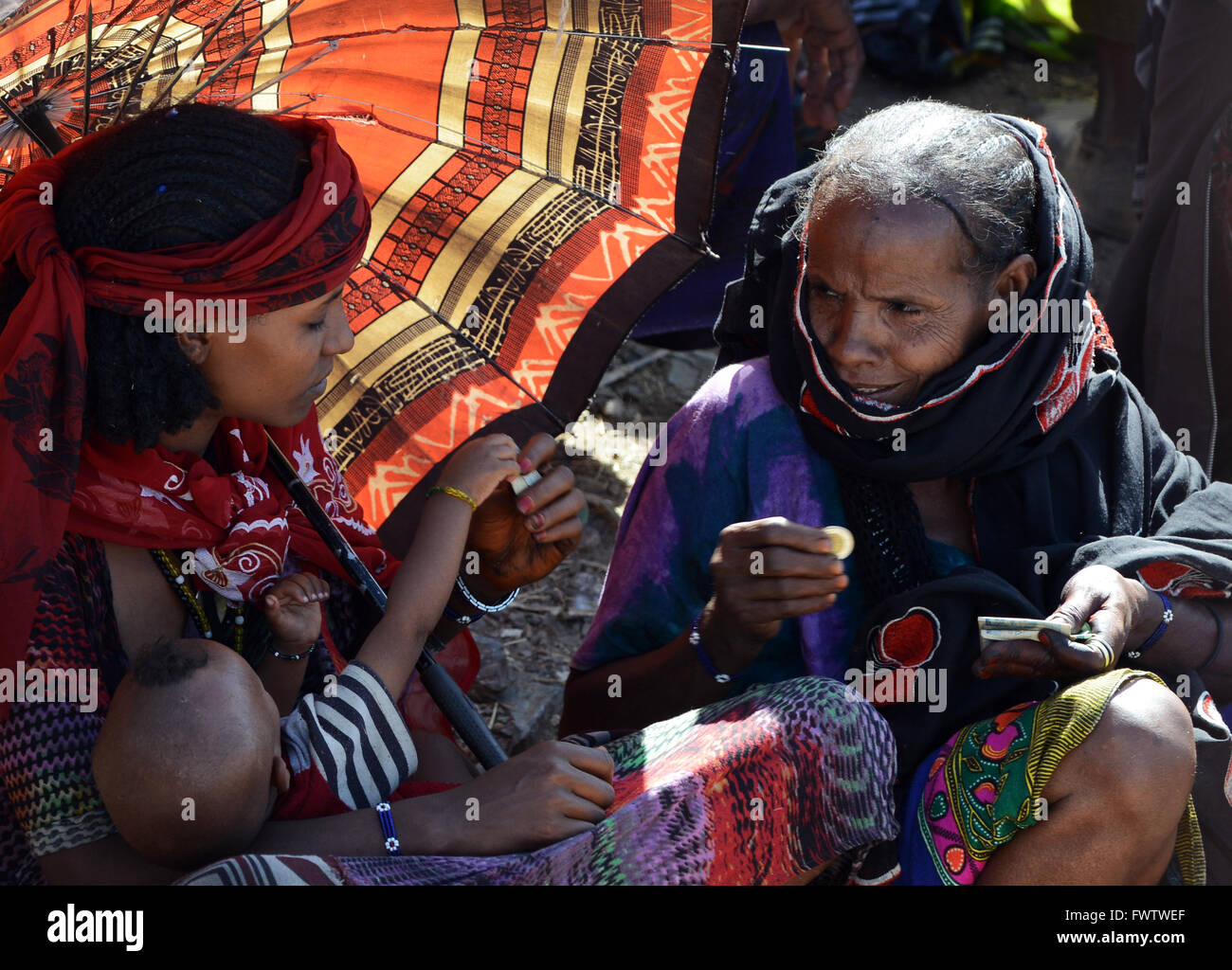 Donne Oromo sotto l'ombrello coloratissimo mercato settimanale bati, Etiopia. Foto Stock