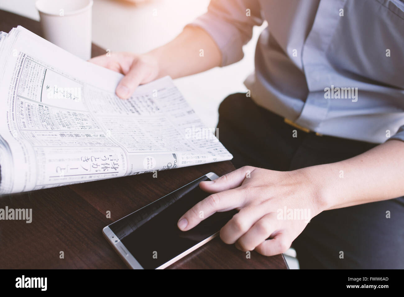 Uomo di mani tenendo il giornale e utilizza lo smartphone per online . Foto Stock