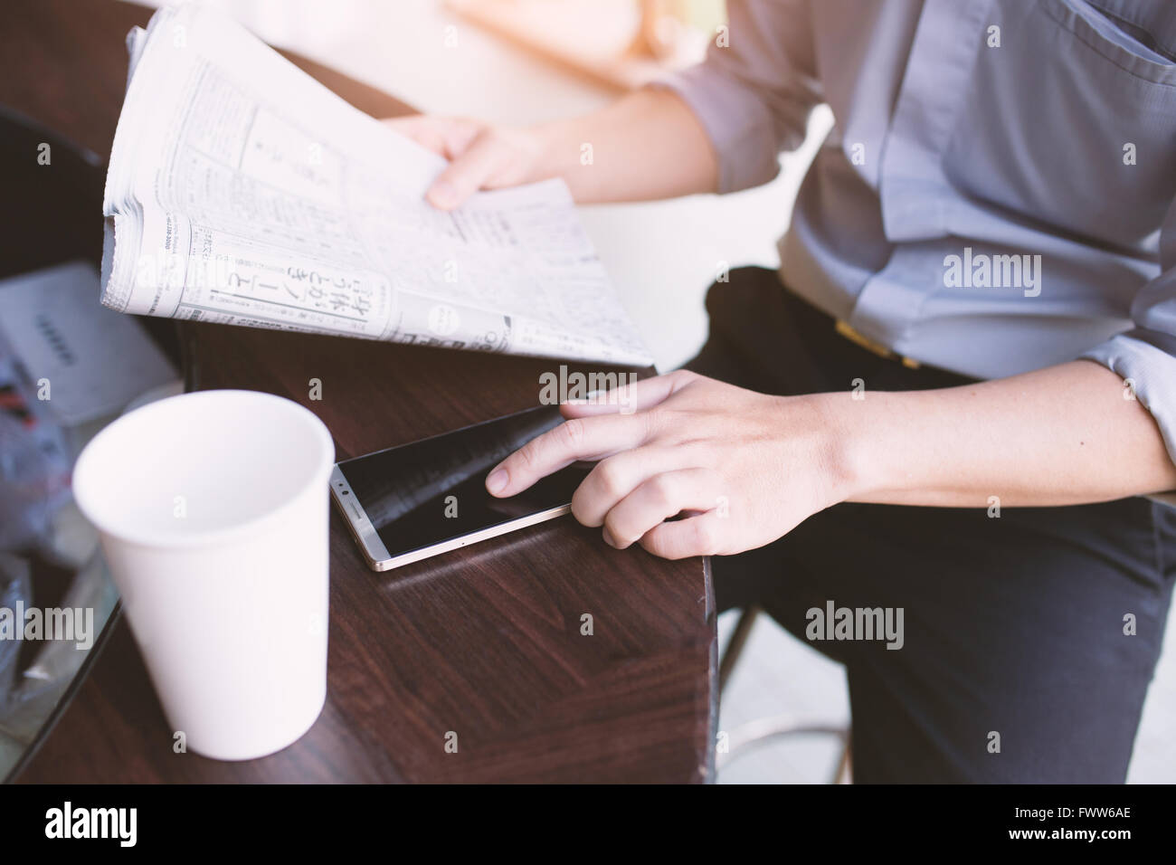 Uomo di mani tenendo il giornale e utilizza lo smartphone per online . Foto Stock