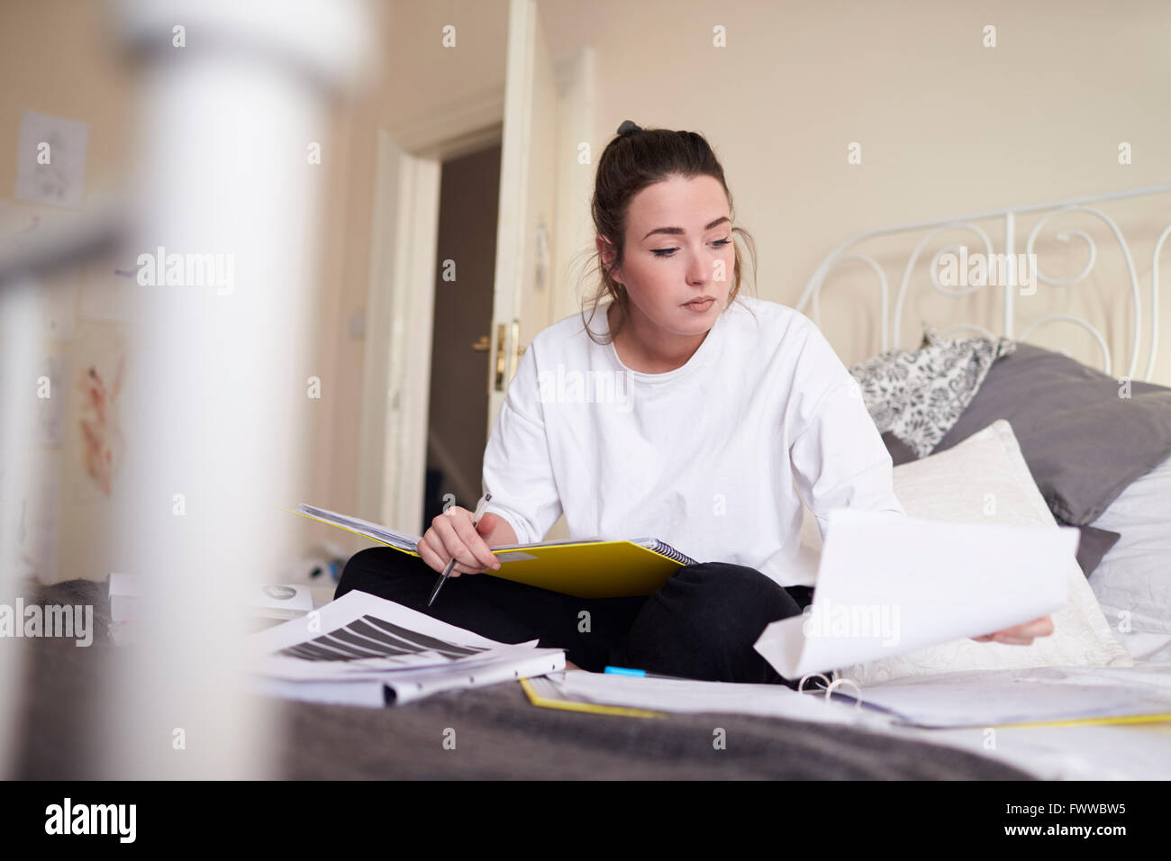 Studentessa lavorando su studi in camera da letto Foto Stock