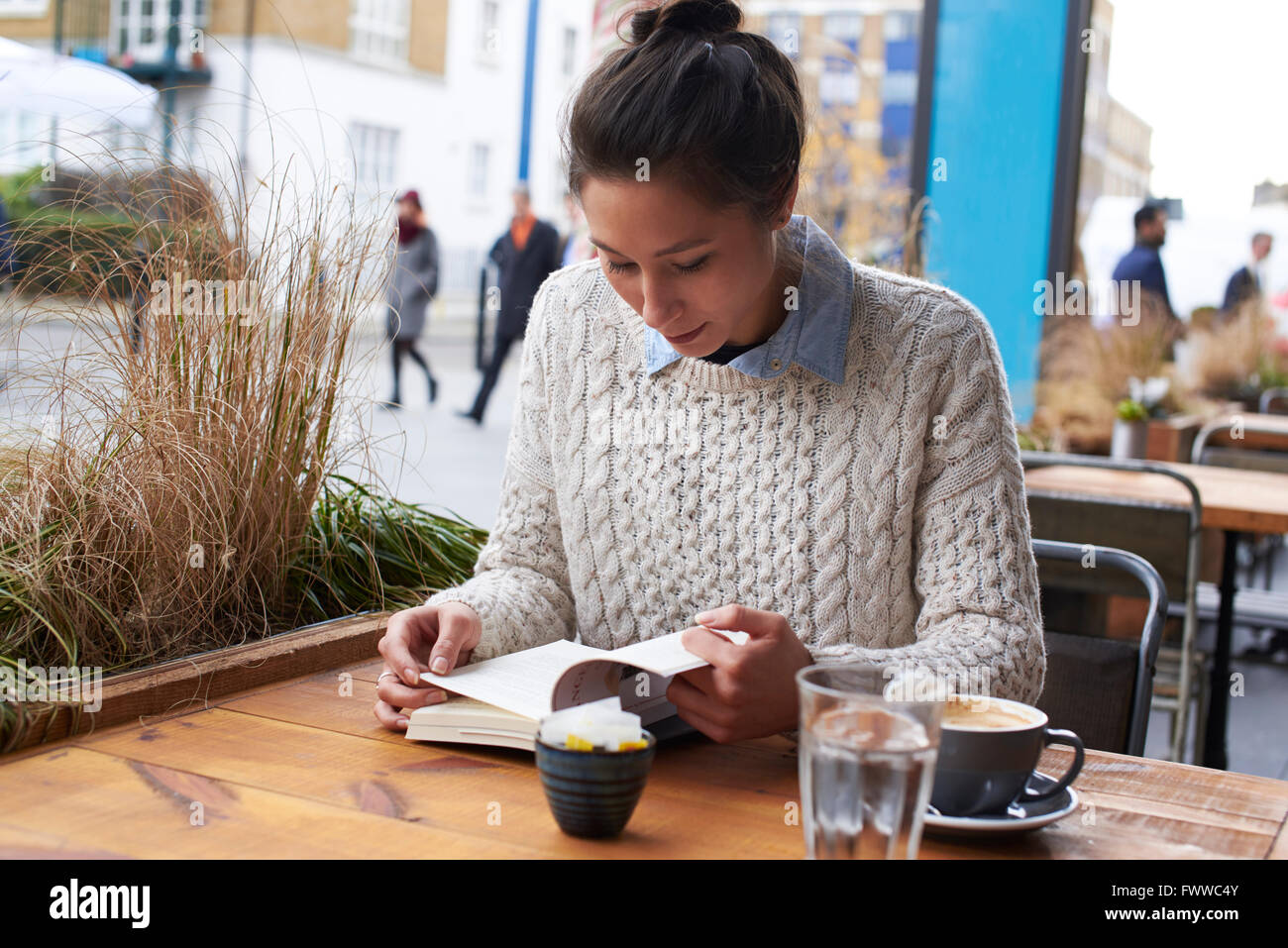 Giovane donna libro lettura In Coffee Shop Foto Stock