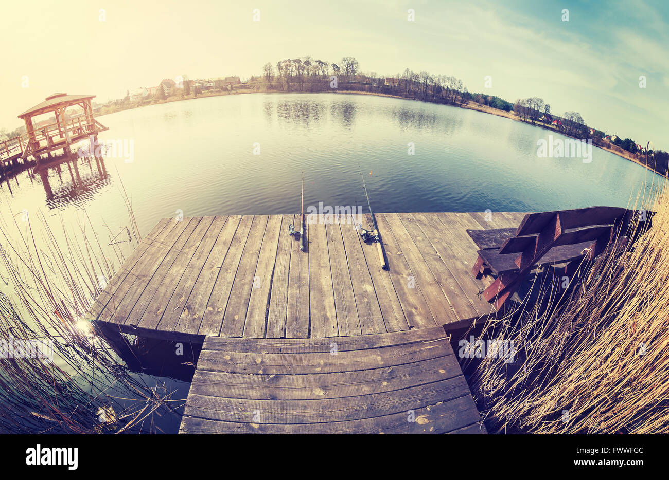 Vintage tonica obiettivo fisheye foto di due canne da pesca sul molo in legno. Foto Stock