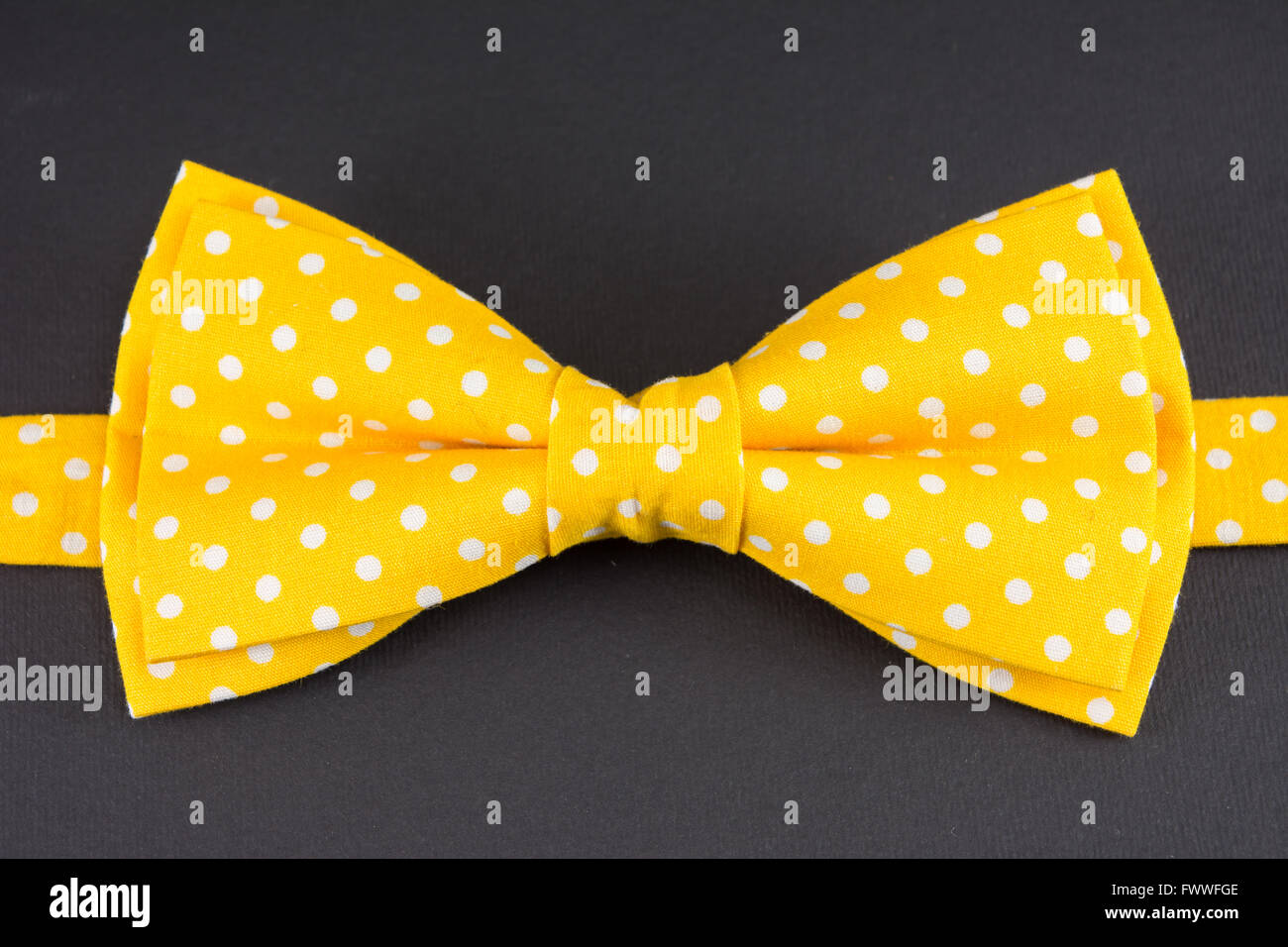 Il giallo il filtro bow tie sulla tavola nera Foto Stock