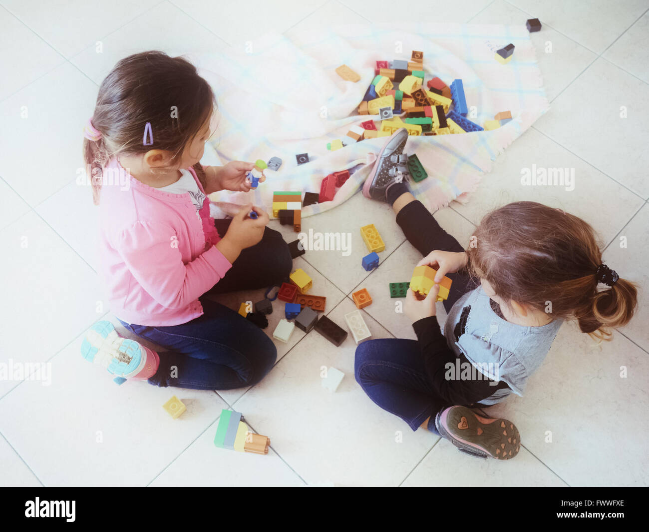 Le ragazze a giocare con i mattoni colorati sparsi sul pavimento Foto Stock