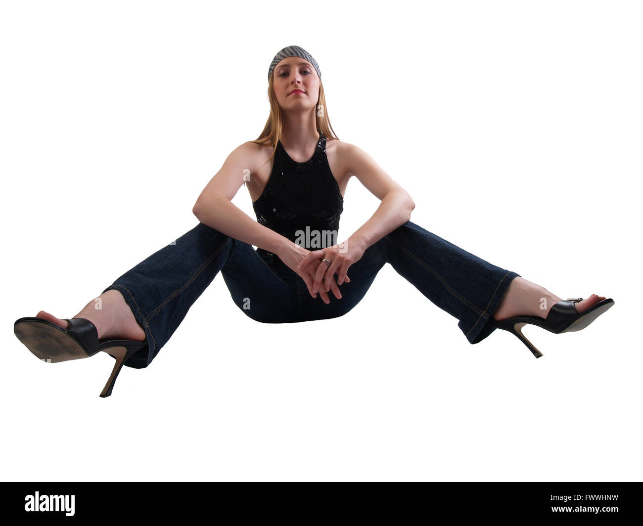 Giovane donna caucasica seduta con gambe divaricate in jeans e tacchi Foto Stock