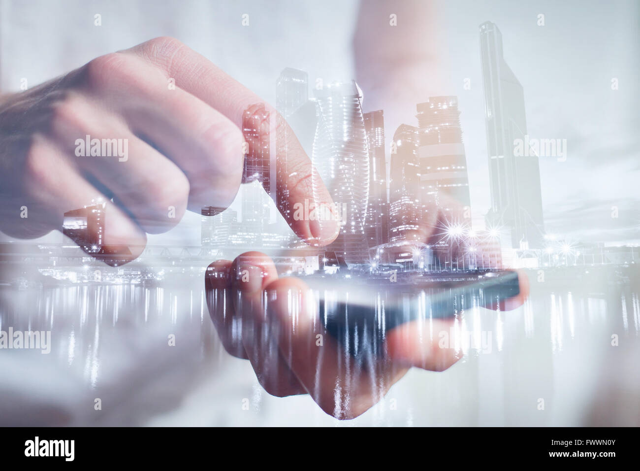 Man mano toccando lo smartphone, closeup, doppia esposizione con moderno skyline della città Foto Stock