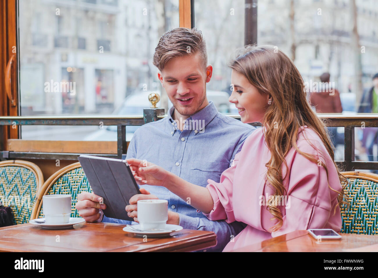 Coppia giovane con tavoletta digitale in cafe, sorridendo felice l uomo e la donna che guarda allo schermo, utilizzando internet, acquistare online Foto Stock