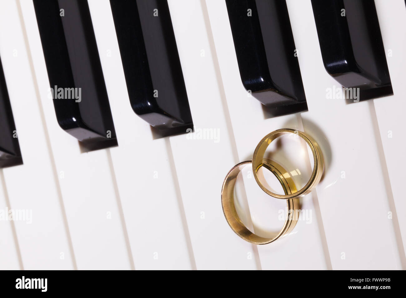 Dettaglio della tastiera di pianoforte e gli anelli di nozze Foto Stock