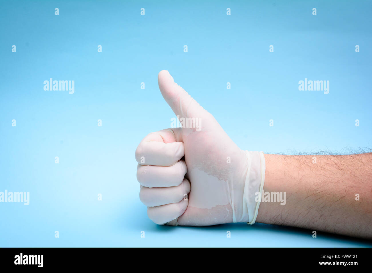 Mano nel guanto di medici su sfondo blu Foto Stock