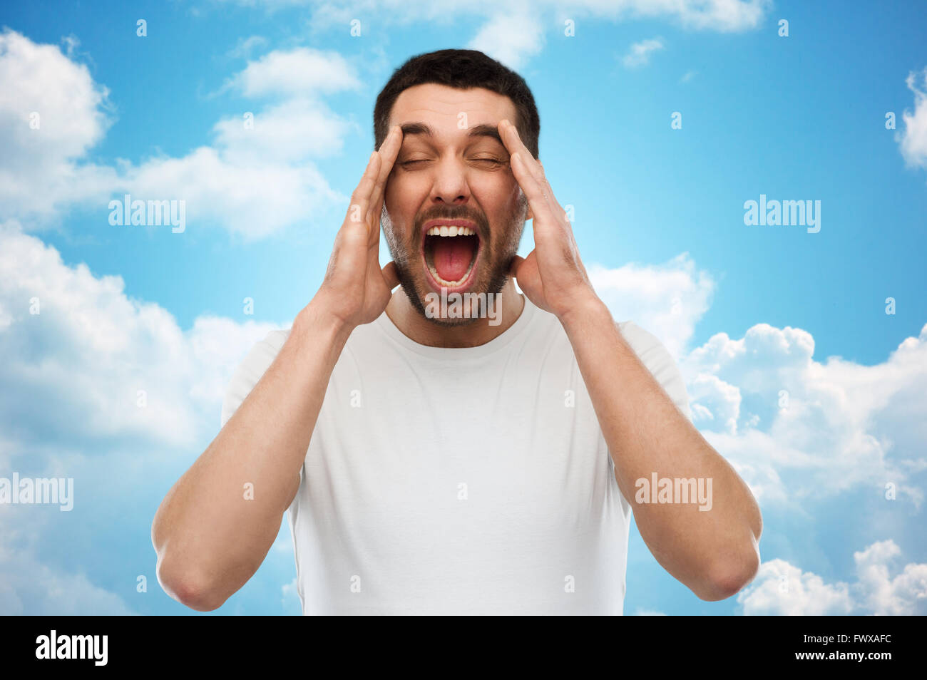 Crazy gridando uomo in t-shirt oltre il cielo blu Foto Stock