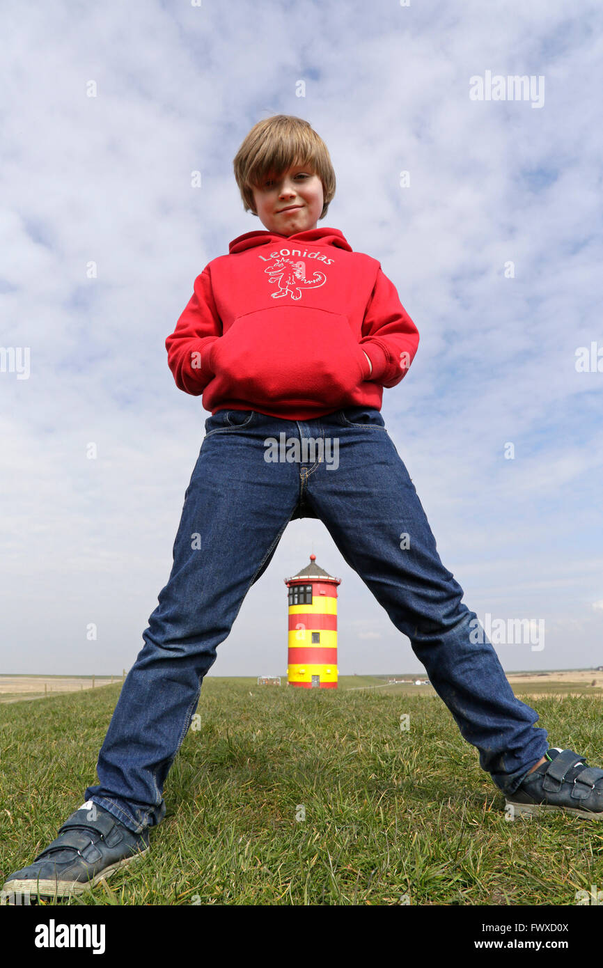 Giovane ragazzo in piedi cavallo di zampe di fronte Pilsum Lighthouse, East Friesland, Bassa Sassonia, Germania Foto Stock