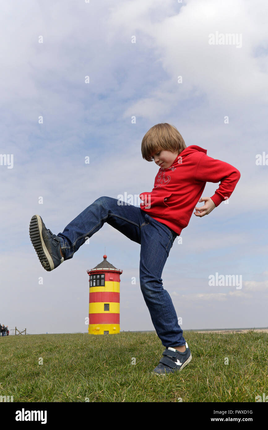Ragazzo giovane a scavalcare Pilsum Lighthouse, East Friesland, Bassa Sassonia, Germania Foto Stock