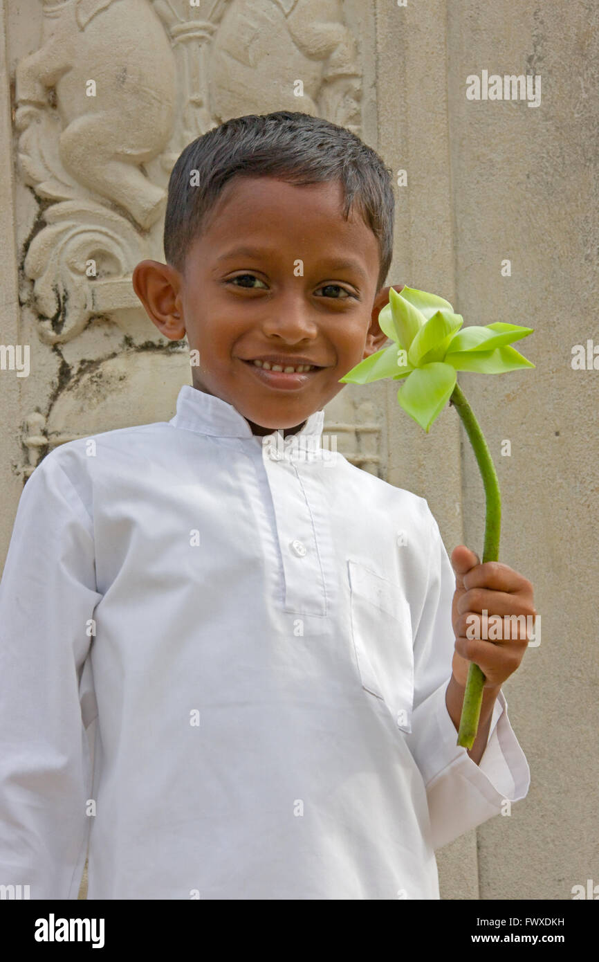 Little Boy tenendo un fiore di loto a Ruwanwelisaya Dagoba, Anuradhapura (Patrimonio Mondiale dell'UNESCO), Sri Lanka Foto Stock