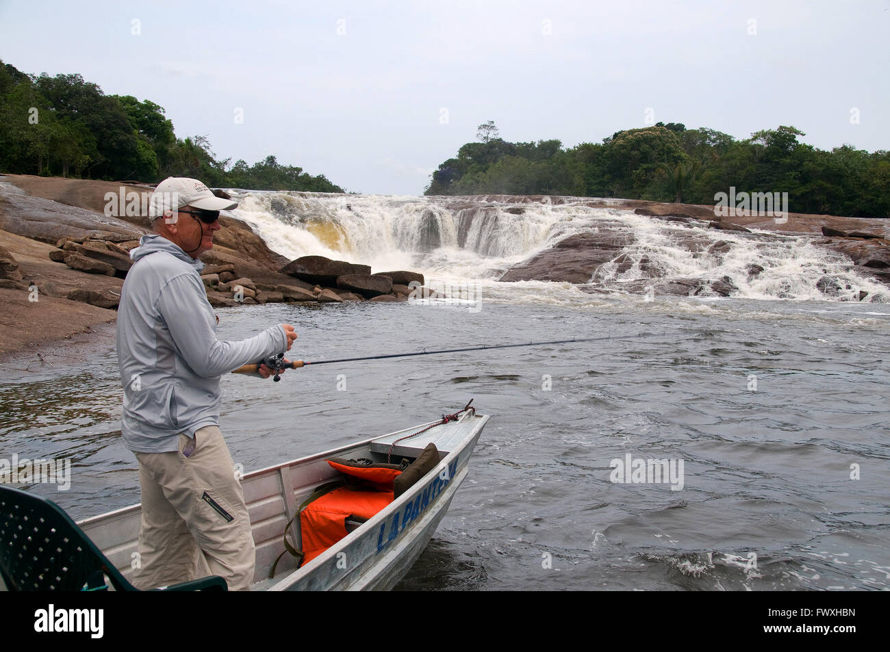 Un pescatore in cerca del gigante payara Dracula bobine di pesce un tappo attraverso la cascata rapide sul colombiano Cano Bocon Inirida (fiume). Foto Stock