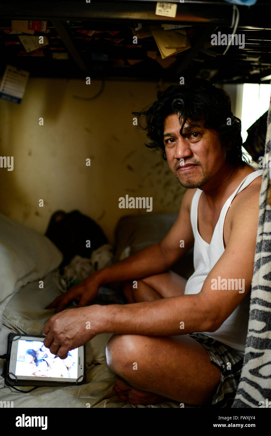 Il Qatar Doha, complesso industriale al di fuori della città, alloggiamento camp per il lavoratore migrante , sei lavoratore filippino condividono un 10 mq di camera, lavoratore Noel comunica da Samsung tablet con la sua famiglia a Manila Foto Stock