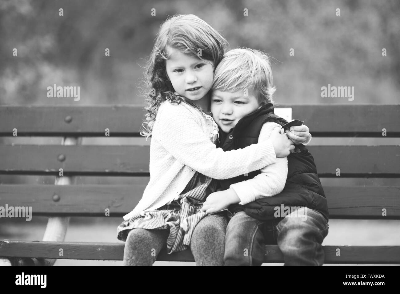 Fratello e Sorella e avvolgente su una panchina nel parco Foto Stock