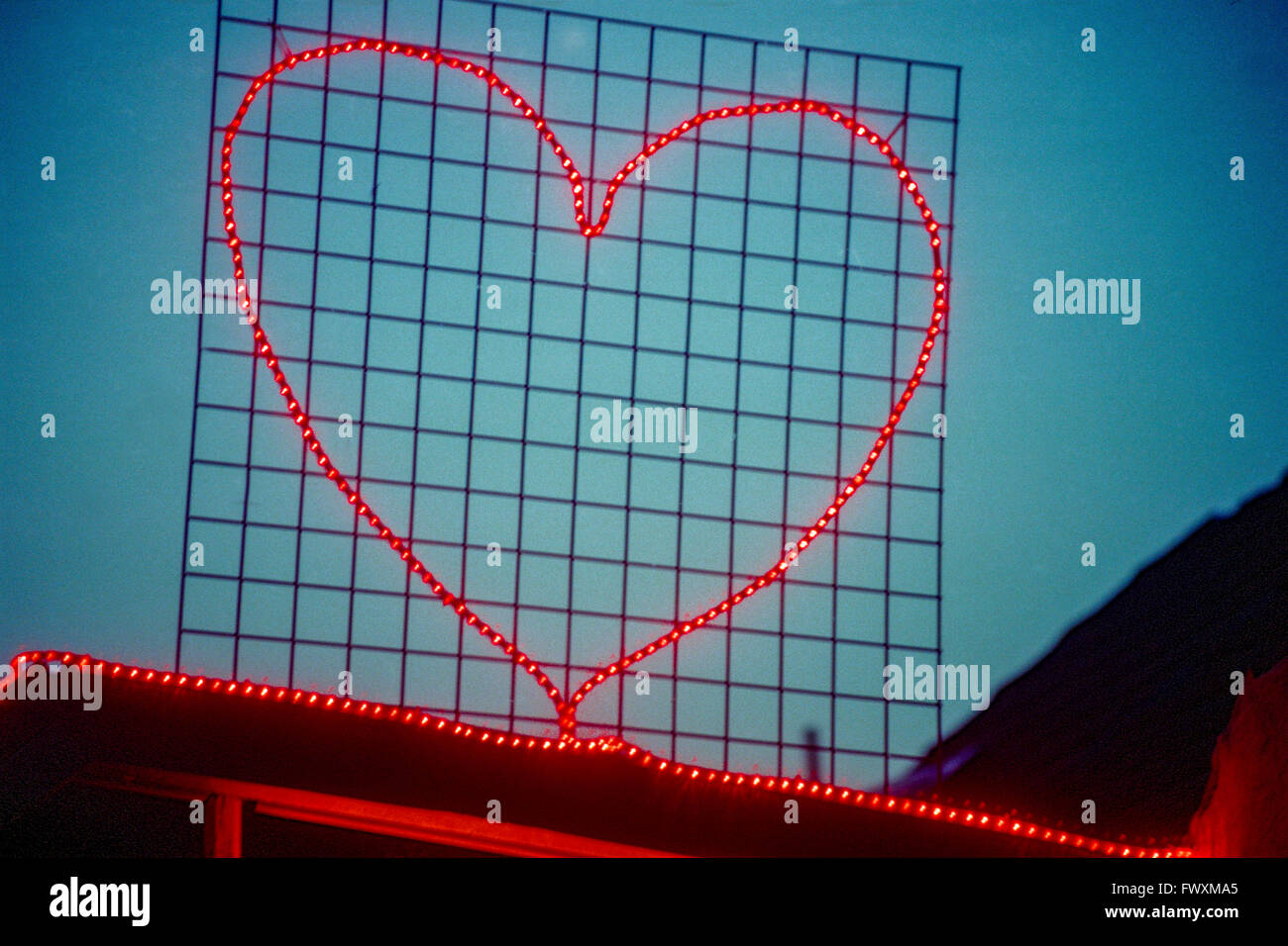 Luce sagomata per amore simbolo a forma di cuore sul tetto della casa Foto Stock