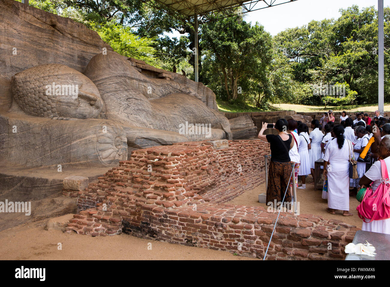Sri Lanka, Polonnaruwa, Gal Vihara visitatori, guardando il Buddha reclinato, nel parinirvana pongono giacente sul lato destro Foto Stock