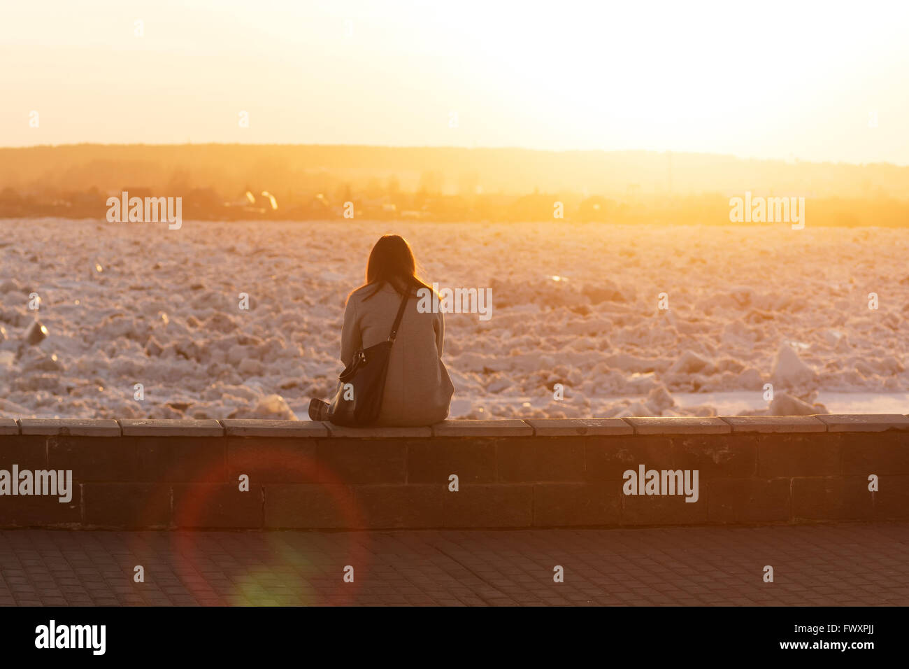 Una giovane donna orologi il ghiaccio sul fiume Foto Stock