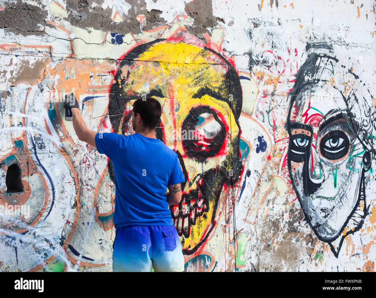 Graffiti artist la spruzzatura su un vecchio graffiti sul muro in Spagna Foto Stock