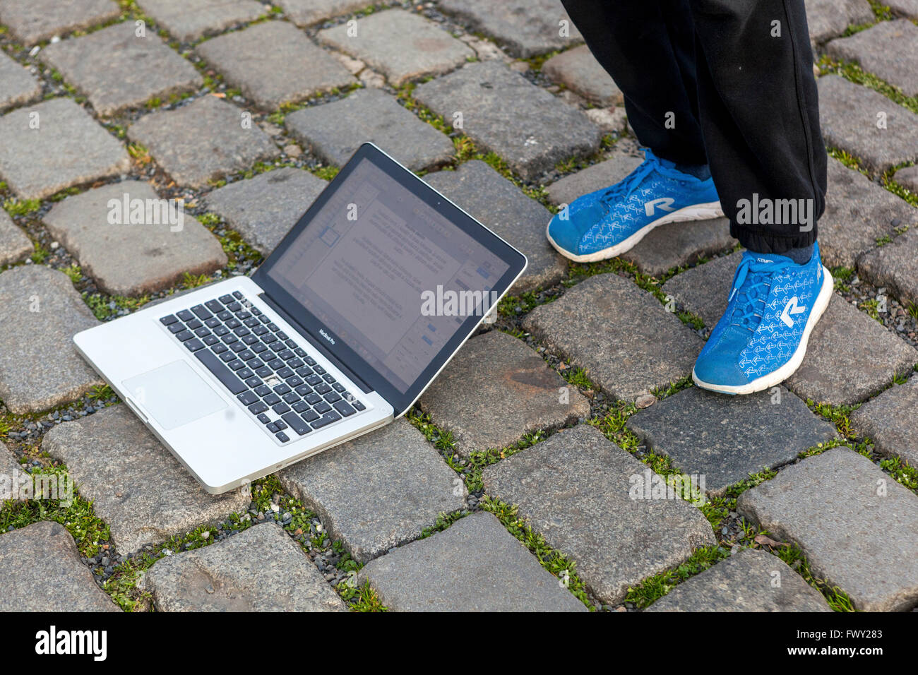 Notebook sdraiato a terra e gambe nelle scarpe sportive, sezione bassa Foto Stock