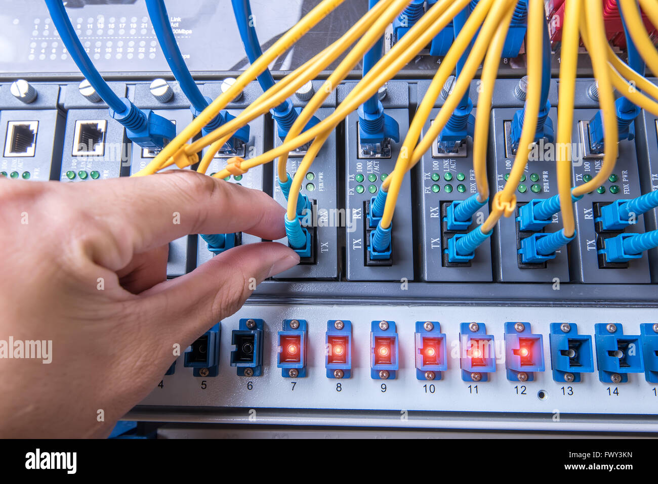 Uomo che lavora nel server del network camera con fibra ottica hub per le comunicazioni digitali e internet Foto Stock