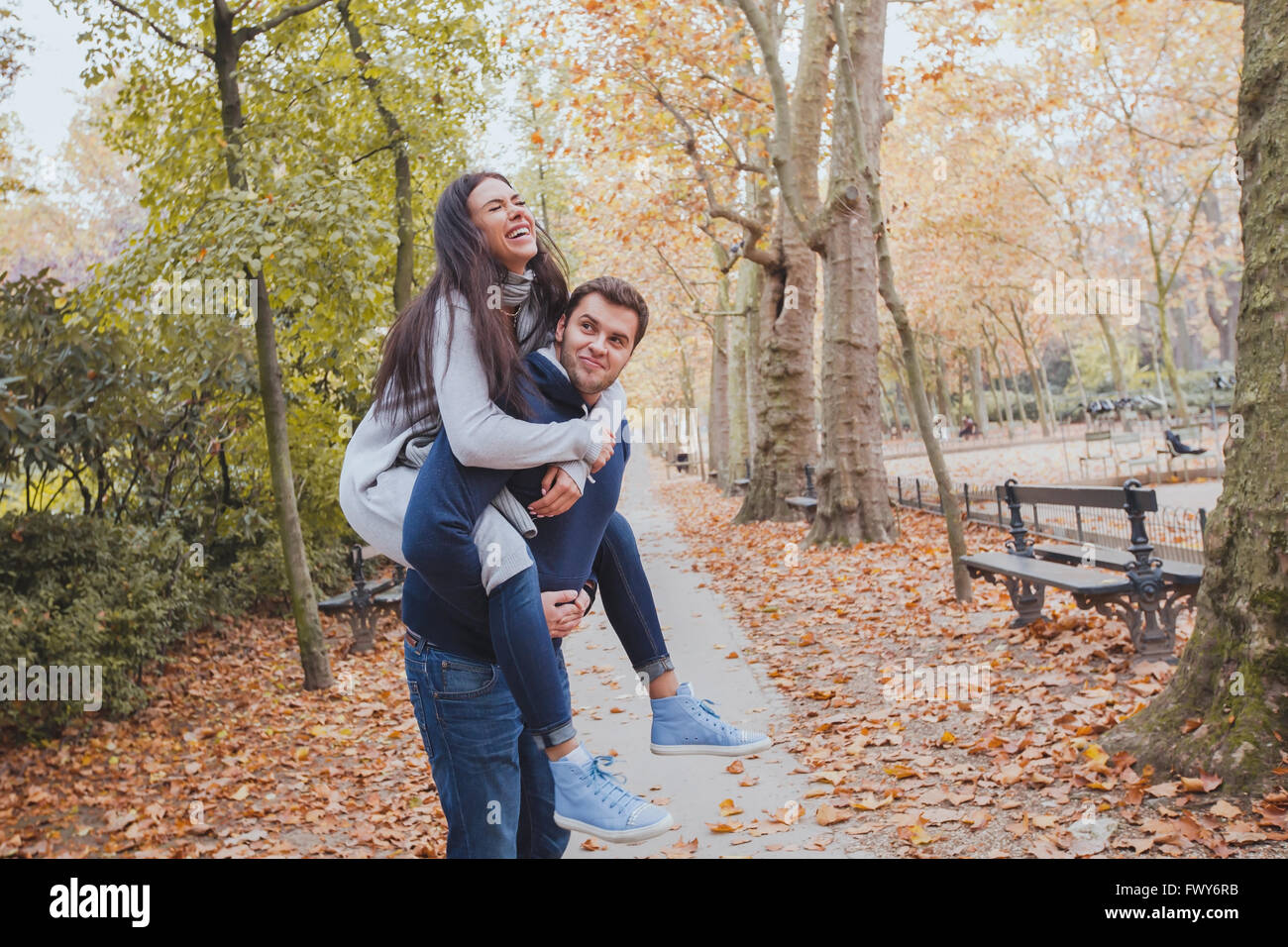 Felice coppia giovane divertendosi in autunno park, famiglia caucasica, uomo e donna, piggyback Foto Stock