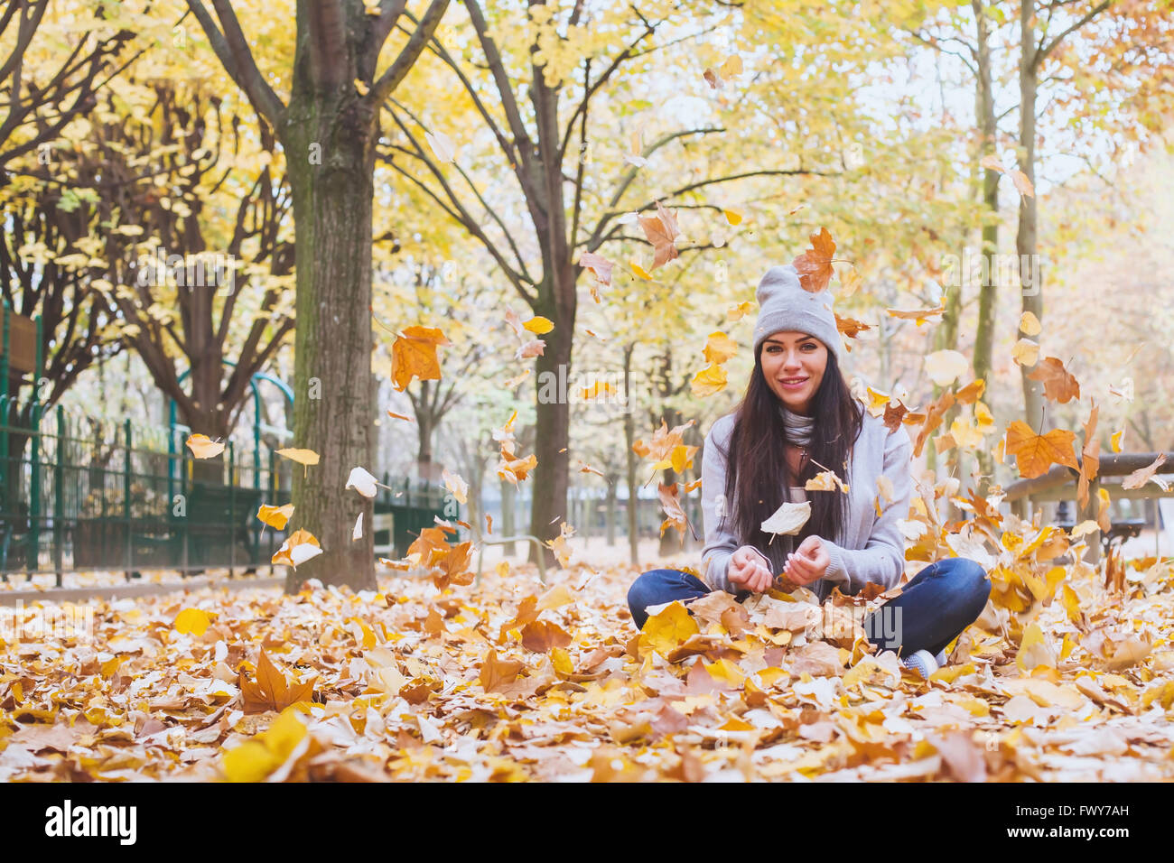 Autunno park, bella donna sorridente e caduta di foglie di giallo Foto Stock