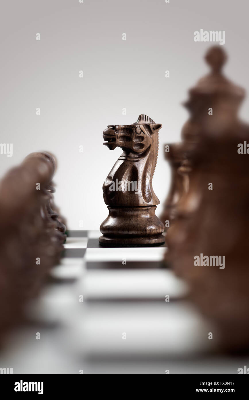 Partita scacchi a personaggi viventi concetto di legno nero cavaliere di scacchi in piedi tra i pezzi sulla scacchiera pronta per la realizzazione di una squadretta di mov Foto Stock