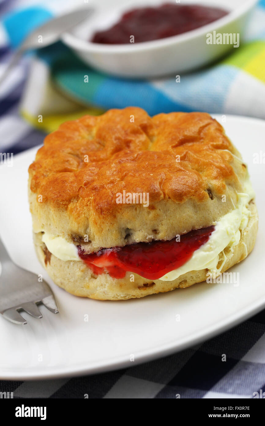 Inglese scone con uvetta con tradizionale clotted cream e confettura di fragole, primo piano Foto Stock