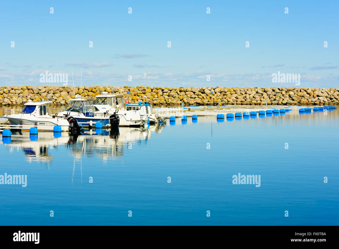 Simrishamn, Svezia - Aprile 1, 2016: incantevole, windless giornata presso la marina in primavera. Molti posti vacanti e il molo di pietra in backgroun Foto Stock