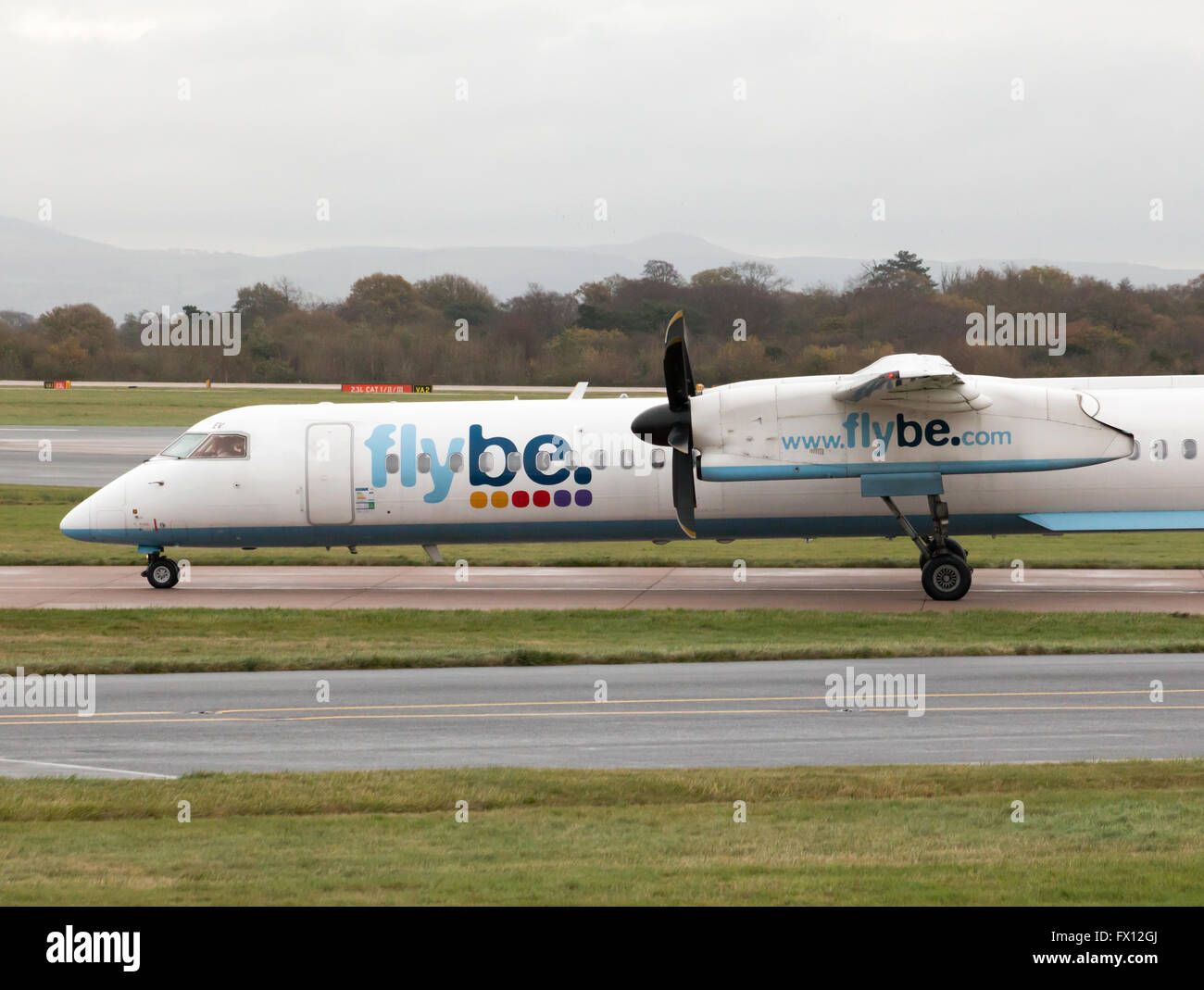 Flybe Bombardier Dash 8 Q400 medio raggio a doppio motore aereo passeggeri (G-KKEV) rullaggio sull'Aeroporto Internazionale di Manchester. Foto Stock